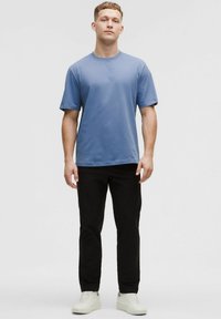 Sinine lühikeste varrukatega t-särk, millel on mugav lõige, koos mustade pükstega ja valgete tossudega. Sile kangas, minimaalne disain, ilma mustriteta.