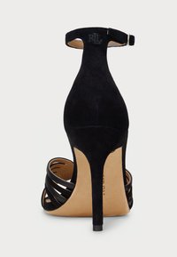 Μαύρη ψηλοτάκουνη σανδάλι με μυτερή μύτη, σουέτ άνω μέρος, λουράκι στον αστράγαλο και σχέδιο πολλών λουριών, με ξυλώδη εσωτερικό και υφασμάτινη σόλα.