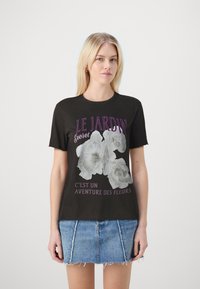 Černé bavlněné tričko s květinovou grafikou a bílým a fialovým textem „LE JARDIN Secret C’est un AVENTURE DES FLEURS.“