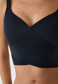 Zwarte, gladde stoffen bh met een wikkeldesign en brede bandjes. Beschikt over een naadloze afwerking en zachte textuur, en biedt volledige dekking.