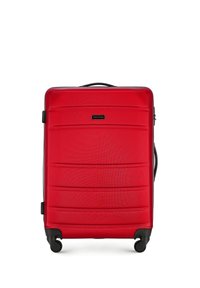Maleta rígida roja con surcos horizontales, fondo negro, cuatro ruedas y un mango extensible para un transporte fácil.