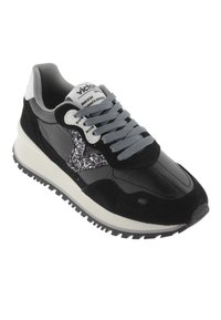 Zapatilla negra y gris con detalles de brillo, cordones grises, suela blanca y cuello acolchado, en ángulo para mostrar la vista lateral y superior.