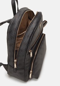 Zaino nero in materiale lavorato, con tre scomparti con zip, accessori color oro e interno foderato con un motivo logo sottile.