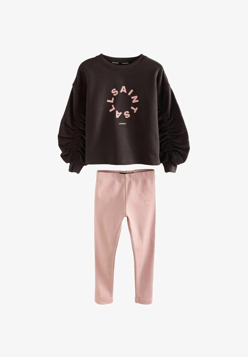 Svart långärmad topp med rynkade ärmar och rosa cirkulär "ALLSAINTS LONDON" logga, kombinerad med ljusrosa leggings med matchande logga.
