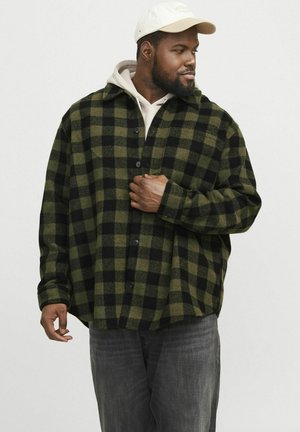 Green and black checkered flannel shirt with a front pocket, long sleeves, and black buttons. Worn over a light grey hoodie.