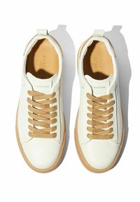 Weiße Leder-Sneaker mit strukturierter Oberfläche, beigen Schnürsenkeln und Gummi-Sohle. Runde Zehenform und minimalistisches Design.