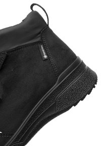 Zwarte enkelboot met een soepel leren bovenwerk, een gestructureerde rubberen zool en een GORE-TEX-label, ontworpen voor duurzaamheid en waterdichtheid.