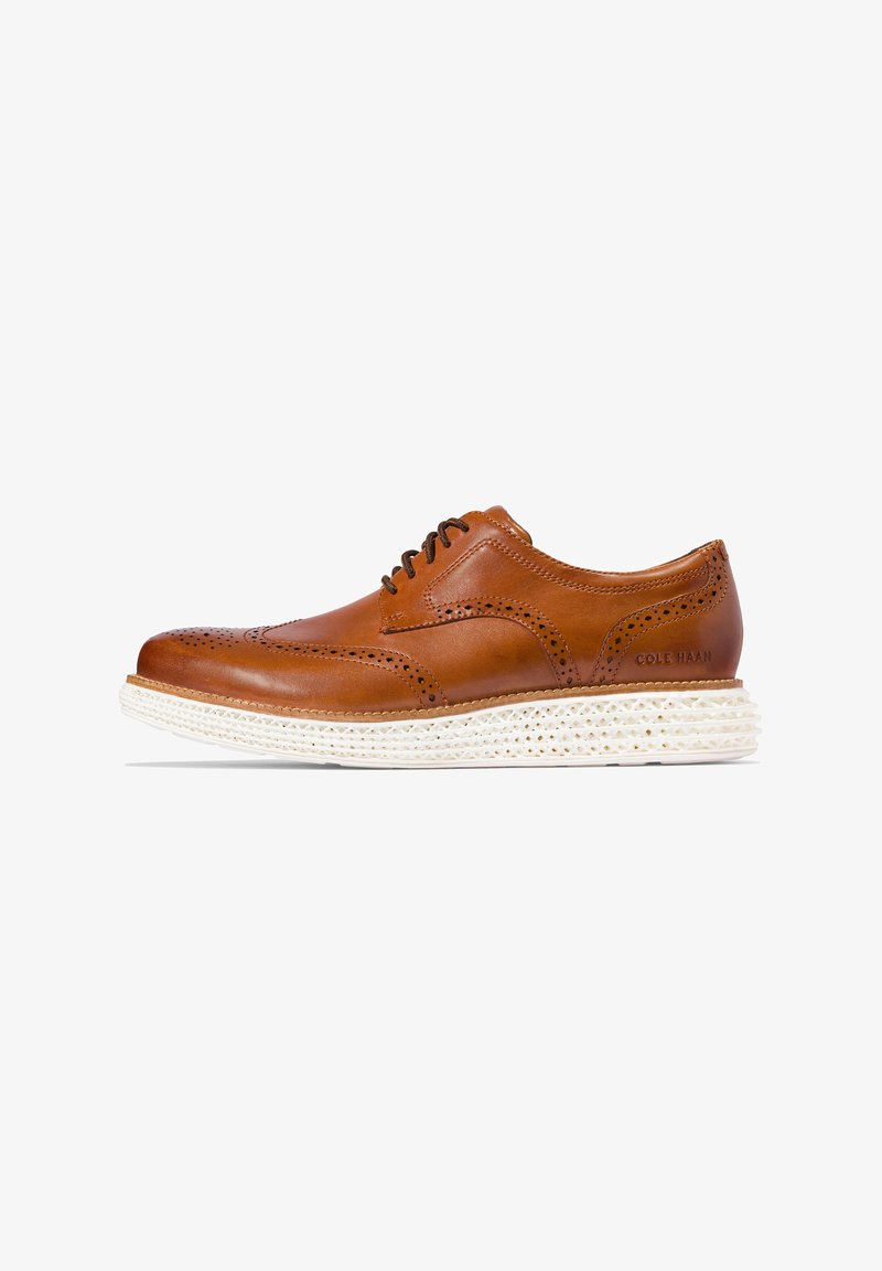 Hnědé kožené formální boty s brogue detaily, kulatou špičkou a bílou texturovanou podrážkou. Disponují tenkými šňůrkami a značkováním na patě.