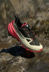 Μαύρο και ανοιχτό μπεζ παπούτσι τρεξίματος για μονοπάτια με ροζ λεπτομέρειες, υφή στο πάνω μέρος και ανθεκτική σόλα. Διαθέτει λογότυπο και ασφαλές σύστημα κορδονιών.