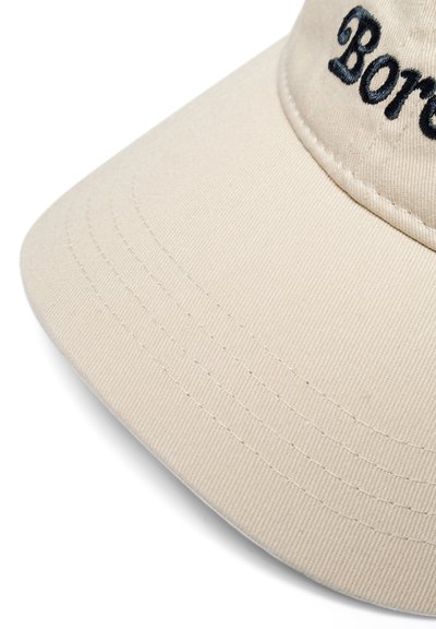 Tan spalvos beisbolo kepurė su juodu siuvinėtu užrašu "Boreas". Pasižymi struktūrizuota krašte matomomis siūlėmis ir tekstūruota medžiagos paviršiumi.