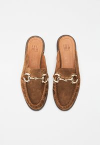 Brown suede slip-on shoes with a rounded toe, featuring a gold-tone chain accent and braided detailing along the edges. Smooth leather insole.