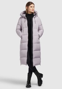 Ljuslila puffjacka med huva, med dragkedja, quiltat mönster, sidofickor och matchad med svarta leggings och stövlar.