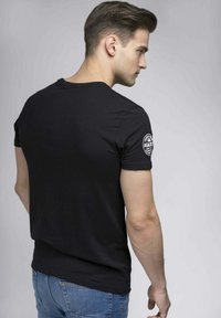Černé bavlněné tričko s krátkým rukávem a kulatým výstřihem, s výšivkou na levém rameni. Slim fit design.