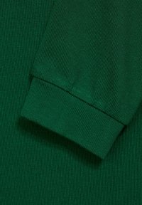 Vihreä ribbikangas hihansuun yksityiskohdalla, jossa näkyy teksturoitu neulekuvio ja sileä viimeistely helmassa.