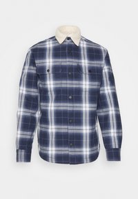 Mörkblå rutmönstrad skjorta med vita och grå linjer, knappstängning fram, två bröstfickor och en mjuk krämfärgad krage.