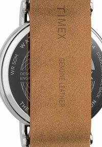 Montre Timex avec un boîtier rond en acier inoxydable, un cadran noir et un bracelet en cuir véritable beige présentant une texture en suède et une gravure de la marque.
