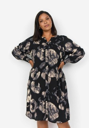 Zwarte jurk met abstracte beige patronen, lange mouwen, v-hals, knopen aan de voorkant en gathers bij de manchetten. Gemaakt van lichte stof.