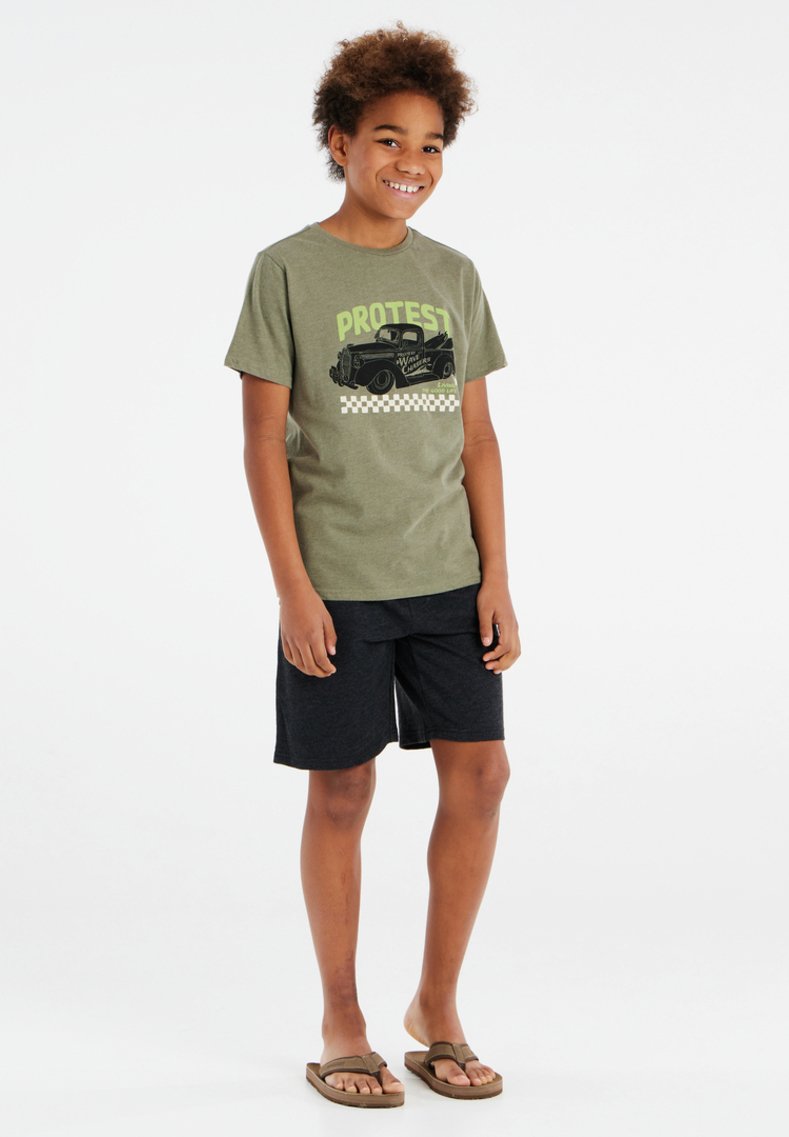 Khaki-T-Shirt mit schwarzem Grafitext "PROTEST" und Vintage-Auto, kombiniert mit dunklen Shorts und braunen Flip-Flops. Lässiger, atmungsaktiver Stoff.