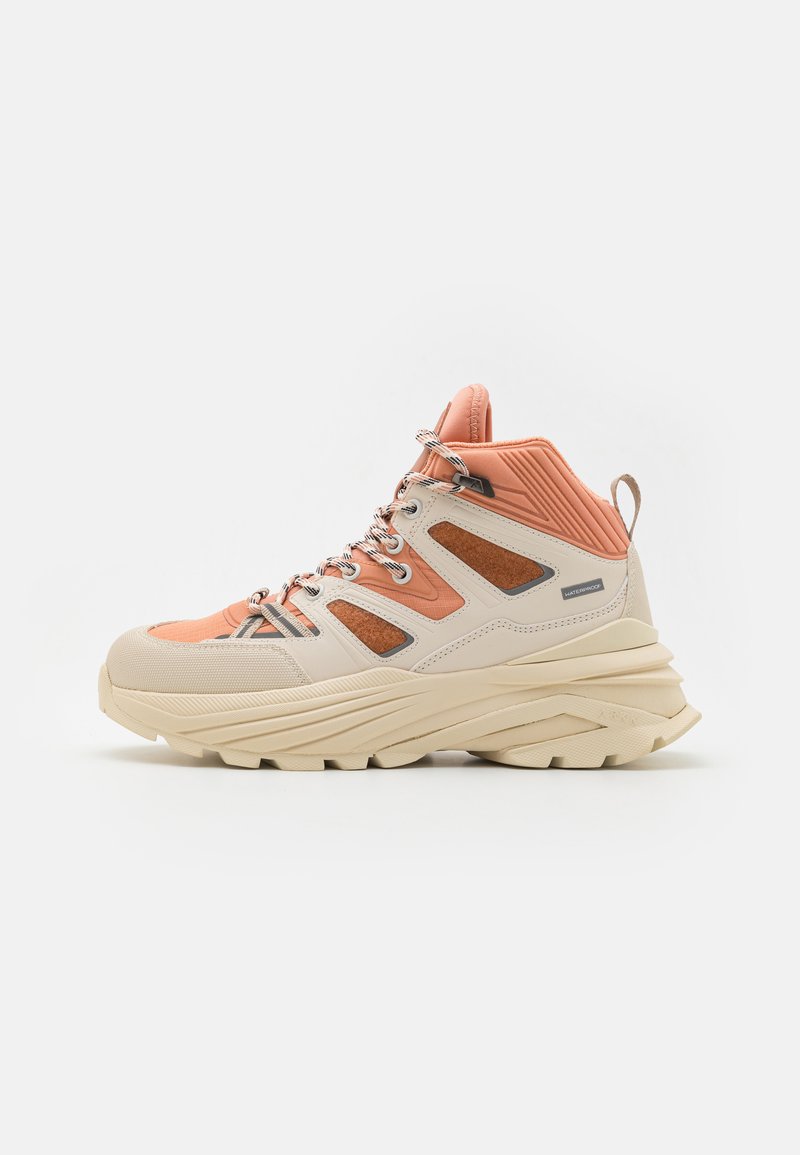 High-top sneakers featuring a cream and peach color scheme, textured material, prominent laces, and a chunky sole with distinct grooves.