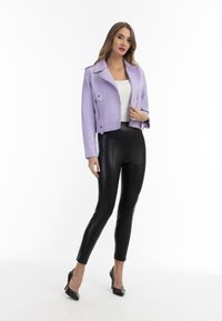Lavender nep leren cropped bikerjack met brede revers, ritszakken en schouderepauletten, gecombineerd met zwarte nep leren legging en hakken.