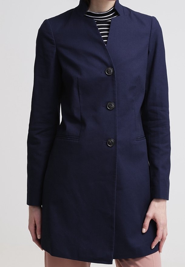 Abrigo entallado de color azul marino con diseño sin cuello, cierre de botones frontal y dos bolsillos laterales. Tejido suave y silueta estructurada.