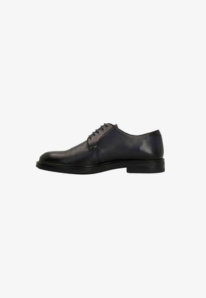 Chaussure oxford en cuir noir avec lacets, bout rond et finition texturée. Présente un talon bas et plat et un design minimaliste.