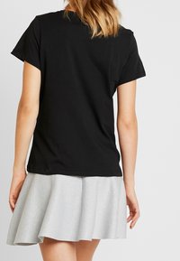 Black short-sleeve t-shirt with rounded neckline, paired with a silver flared skirt featuring a subtle shimmer and a smooth texture.
