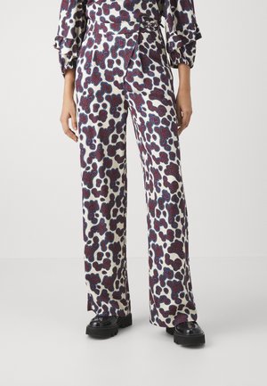White patterned trousers featuring a bold abstract design in deep red and blue. The fabric is smooth, and the fit is wide-leg, with a high waist.