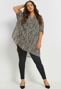 Top in stile kimono a righe bianche e nere con una vestibilità ampia, caratterizzato da un collo a camicia e maniche corte, abbinato a pantaloni skinny neri.