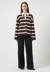 Brązowo-biały sweter w paski z dzianiny z kołnierzykiem, trzema guzikami i luźnym krojem, zestawiony z czarnymi szerokimi spodniami jeansowymi.