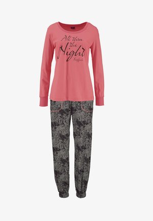 Rosa Langarmshirt mit schwarzem Schriftzug, kombiniert mit schwarzen, floral gemusterten Hosen mit rotem Stich und elastischen Bündchen an den Knöcheln.