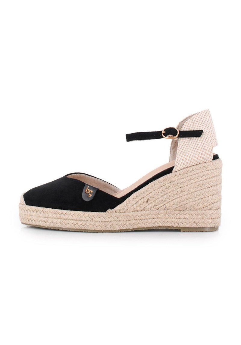 Espadrille de cuña de ante negro con suela de yute trenzado, correa en el tobillo y un detalle de tela estampada en la parte trasera. Detalle del logo en dorado.