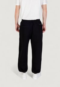 Zwarte sweatpants met een ontspannen pasvorm, elastische tailleband en twee achterzakken. Draag ze met witte sneakers en een eenvoudig wit T-shirt.