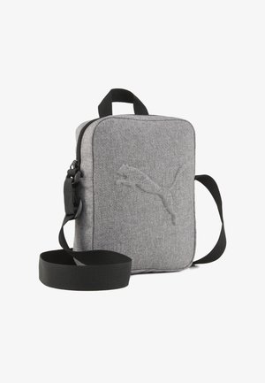 Szary materiałowy plecak na ramię o teksturowanym wykończeniu, z czarnym regulowanym paskiem i wytłoczonym logo z przodu. Kompaktowy prostokątny kształt.