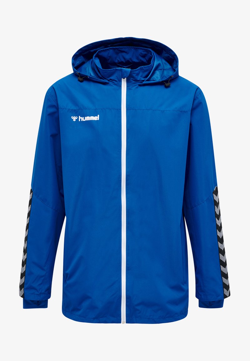 Giacca a vento blu con zipper bianco, dotata di cappuccio, con motivo a chevron bianco e nero sulle maniche e un logo sul petto.