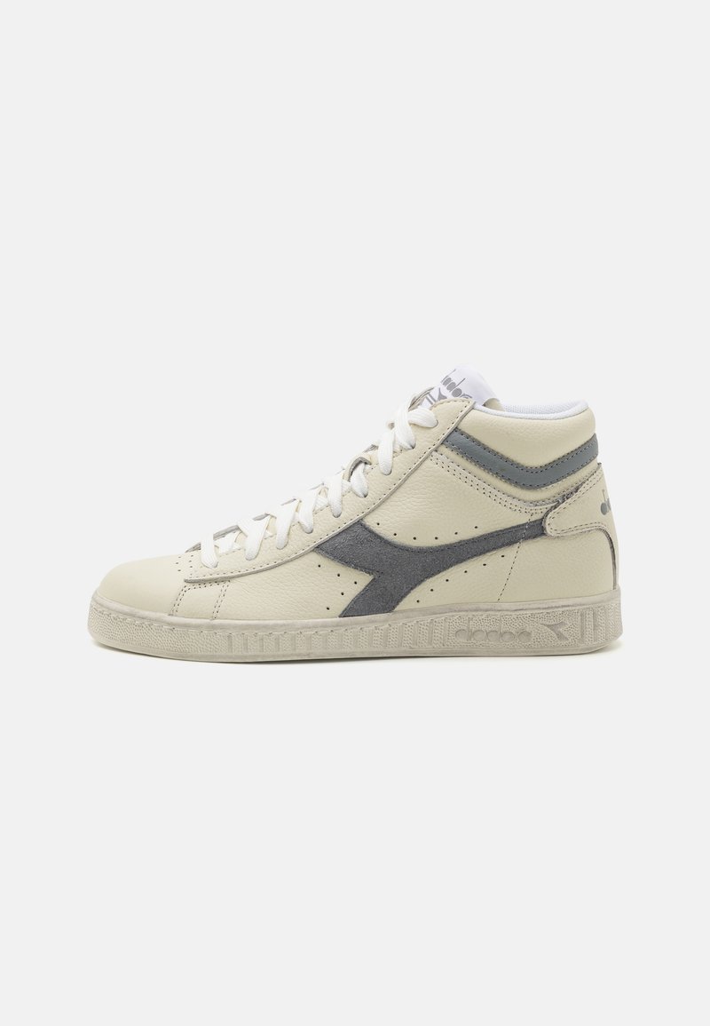 Basket montante couleur crème avec lacets blancs, logo en daim gris, bande grise au talon et semelle texturée sur fond blanc.