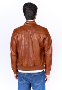 Bruine leren bomberjack met ribgebreide mouwen en zoom, voorzien van een gestikt ontwerp op de rug en een subtiele logo-detail.