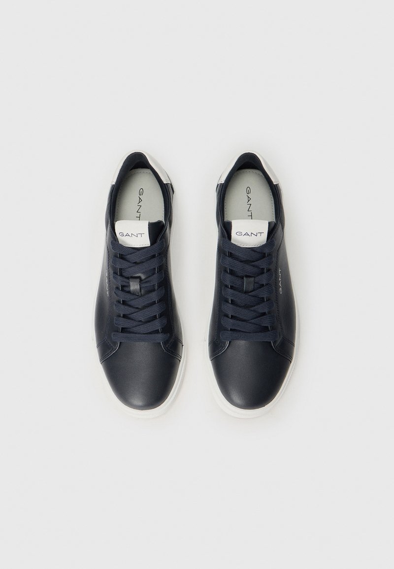 Zapatillas de cuero navy con suelas y cordones de goma blanca. Presentan una lengua acolchada y detalles del logotipo en los laterales y en la parte superior.