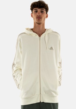 Felpa con zip di colore crema, con polsini e orlo a coste, caratterizzata da tre strisce orizzontali su ciascun manica e un piccolo logo sul petto.