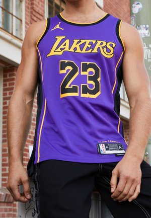 Paarse basketbaltrui met de tekst "LAKERS" in geel, nummer "23" in zwart en geel, met een zwart zijpaneel en label aan de zoom.