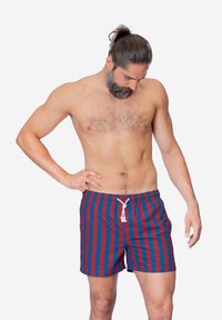 Costumi da bagno a righe in blu e rosso, con vita regolabile e vestibilità rilassata. Realizzati in tessuto leggero con una superficie liscia.