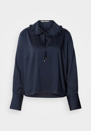 Tengerészkék blúz fodros gallérral és elöl megkötővel, hosszú ujjakkal, mandzsetta részletekkel, sima anyagból készült. Rövidített szegéllyel.