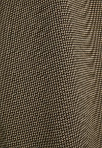 Tissu présentant un motif pied-de-poule en brun foncé et beige. Le tissu a une texture lisse avec un tissage serré.