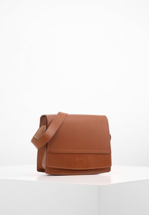 Brun læder crossbody-taske med flaplukning, justerbar rem og subtilt præget mærkelogo foran, vist på hvid overflade.