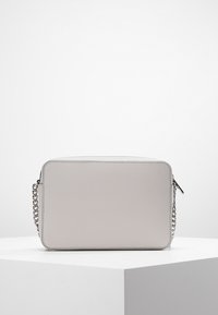 Obdélníková crossbody taška ve světle šedém syntetickém materiálu. Obsahuje řetízkový popruh a hladký povrch s uzávěrem na zip.