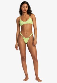 Green floral bikini set featuring a triangle top and low-rise bottoms with thin straps and gathered detailing.