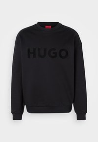 Black sweatshirt made of soft material, featuring a round neckline and long sleeves. The word "HUGO" is prominently displayed in a glossy black font.