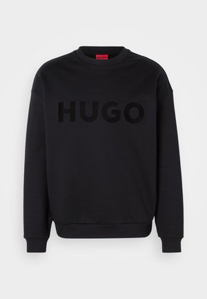 Sudadera negra hecha de material suave, con un escote redondo y mangas largas. La palabra "HUGO" está mostrada de manera prominente en una fuente negra brillante.