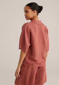 Rosarosa linne skjorta med korta ärmar, spetsig krage och avslappnad passform, i kombination med matchande shorts. Slät textur, minimal detaljering.