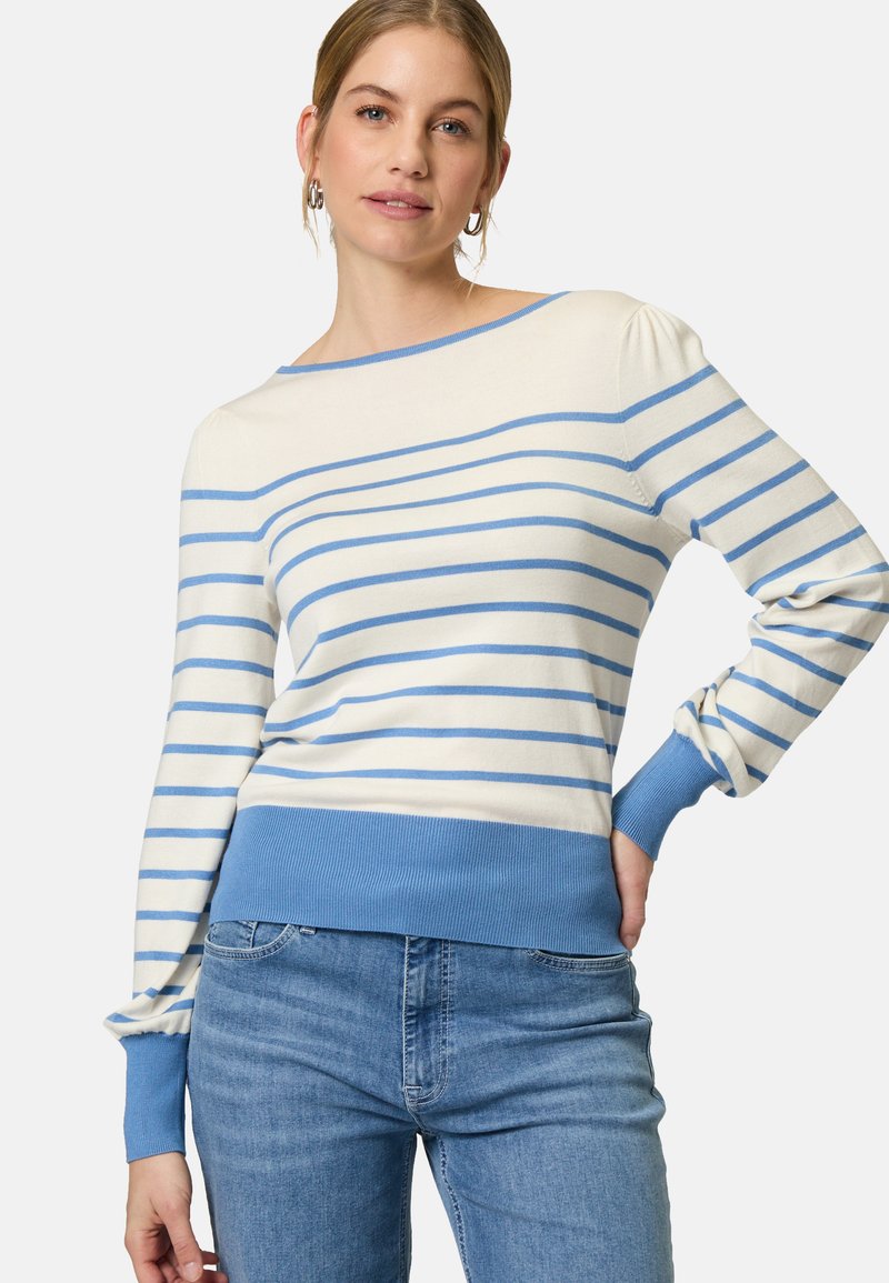 Maglione a righe in crema e azzurro chiaro. Presenta un ampio scollo, polsini e orlo a coste, e una texture morbida. Abbinato a jeans chiari.